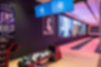 Indoor bowling lanes with ball racks and overhead screens